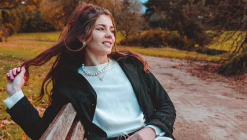 Portrait au rendu vintage d'une jeune femme sur un banc en automne