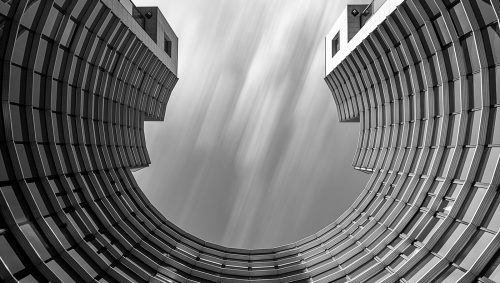 Un batiment de bureau , architecture contemporaine de métal et verre. Le batiment est en arc de cercle. La vue en contre plongée peur faire penser à un vaisseau spatial. 