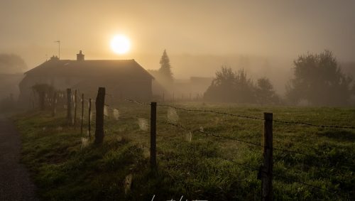 Lever de soleil par un temps brumeux derriere une maison à Champroy