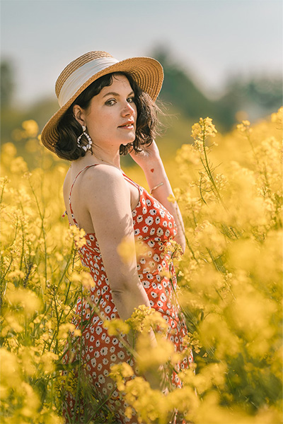femme avec une rovbe rouge, dans un champs colza jaune et un ciel bleu, illustrant l'harmonie triadique