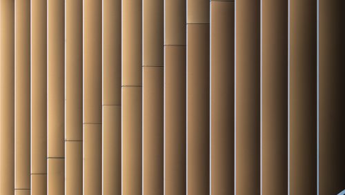 Détail architectural de la Maison de l'innovation à Nantes, montrant des lamelles verticales métalliques de couleur bronze, structurées par des lignes diagonales argentées.