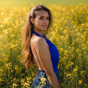 Femme en bleu dans un champ de colza, éclairée à contre-jour.
