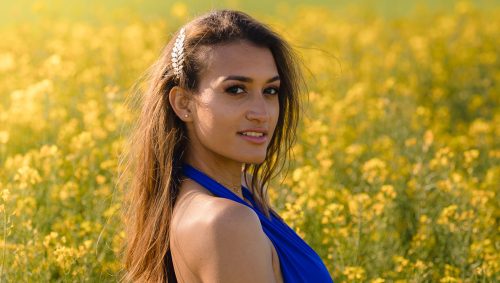 Femme avec un top bleu à contre-jour dans un champs de colza
