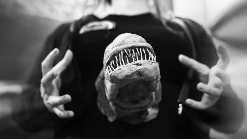 Portrait en noir et blanc d'une personne criant de surprise avec un "chestburster" d'Alien entre les mains, pour Halloween.