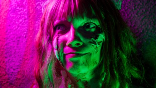 Portrait d'une jeune femme déguisée en mariée zombie pour l'Halloween, avec du maquillage macabre et un sourire subtil.