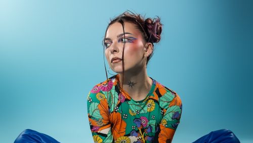 Portrait studio d'une femme assise regardant vers le haut. Style coloré et original.