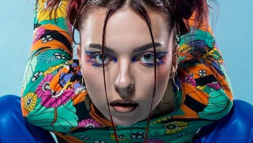 Portrait créatif en studio à Nantes, jeune famme maquillée, accroupi et penchée vers l'objectif.