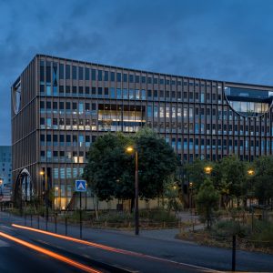Architecture moderne de la maison de l'innovation à heure bleue, avec des traînées lumineuses de voitures au premier plan