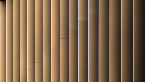 Reflet dorée sur les surfaces métallique des brise-soleil verticaux linéaires.