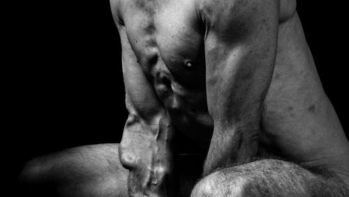 Portrait artistique en noir et blanc d'un homme nu, montrant le torse et les jambes, les détails musculaires et vasculaires étant mis en évidence.