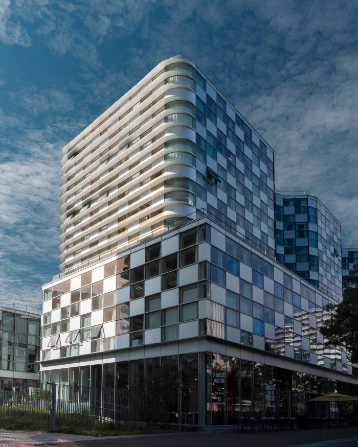 Photographie architecture extérieure : vue d'un immeuble moderne blanc et bleu avec un ciel nuageux bleu en arrière-plan.