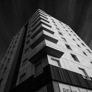 Un batiment avec un eclairage latéral vue en contre plongée éditée en noir et blanc, donnant une photographie d'architecture très dynamique