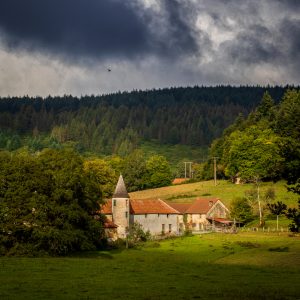 Le chateau de Peyrusse dans la creuse, le ciel est couvert et le chateau éclairé par une percée dans les nuages - patrimoine naturelle et architecturale